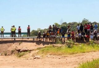 Equipes de busca e resgate em operação em um rio, representando a procura por um desaparecido.