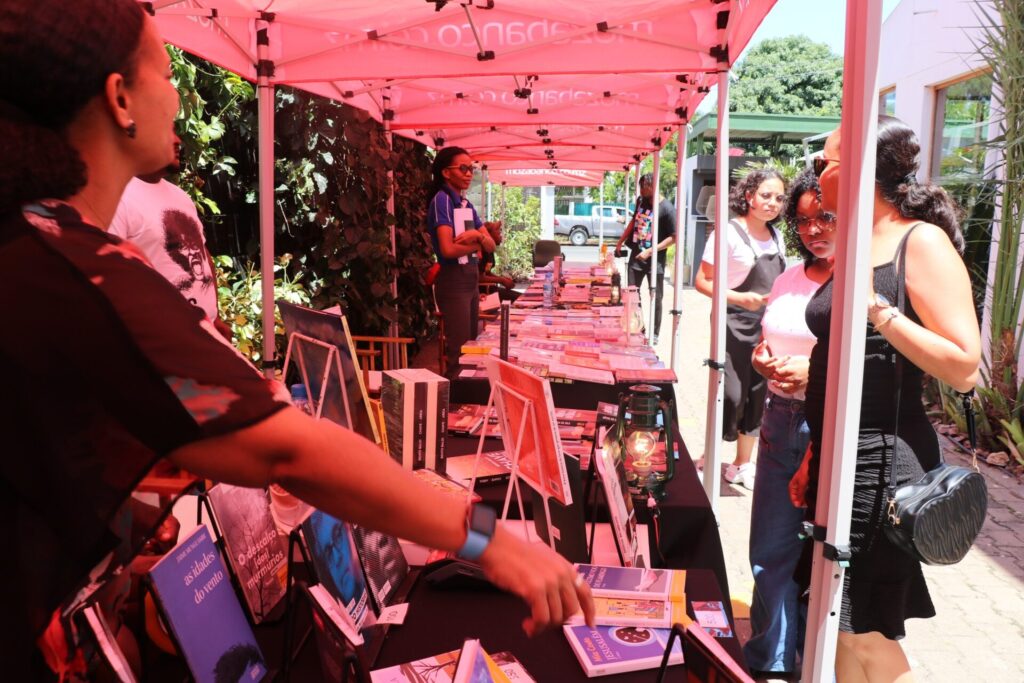 Espaço da Feira do Livro de Maputo com livros expostos e ambiente cultural.